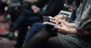 Woman sitting at a conference taking notes